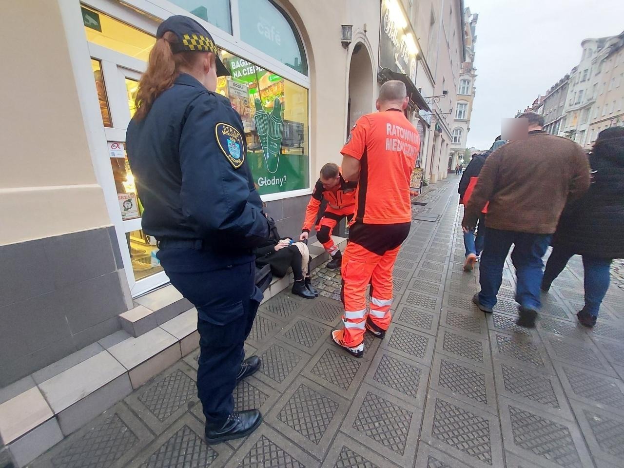 Wielka: młoda kobieta straciła przytomność i upadła na chodnik. Strażnicy udzielali jej pomocy