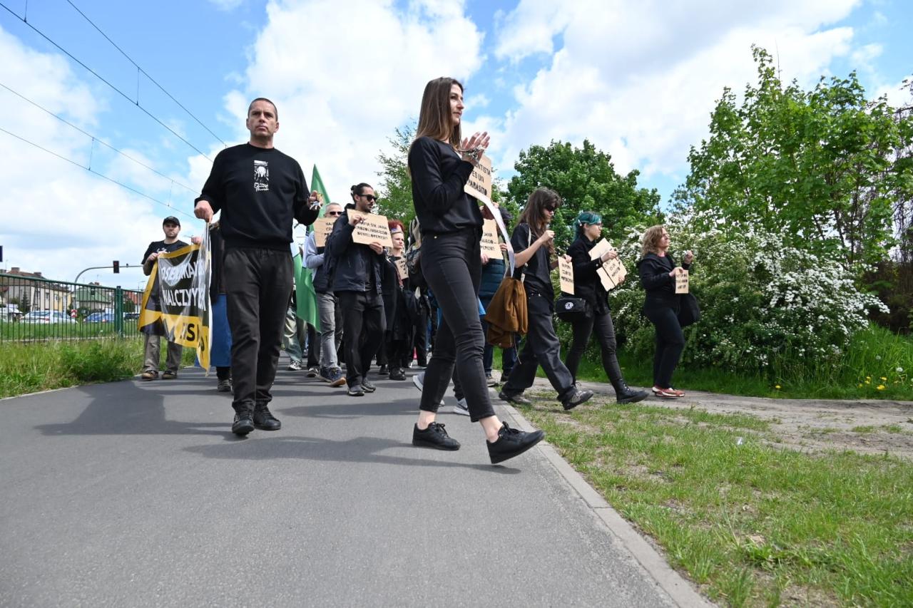 Symboliczny marsz idzie ulicami Poznania. Ubrani na czarno uczestnicy niosą transparenty i klucze