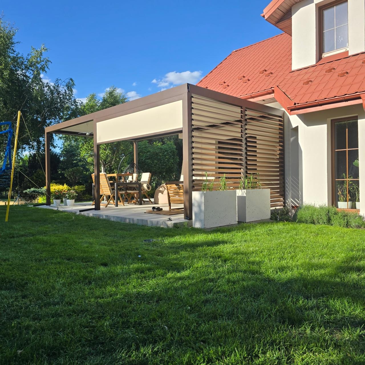 Pergola automatyczna z roletą ekranową i ściankami stałym z obrotowymi shutters. Zdjęcie jest własnością firmy Variant.